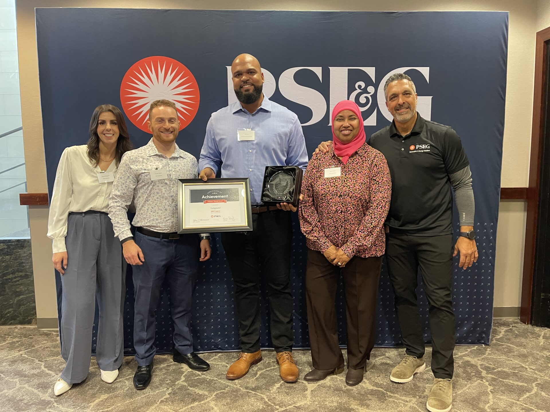 Group standing in front of PSE&G banner as Vanguard receives award from Direct Install program